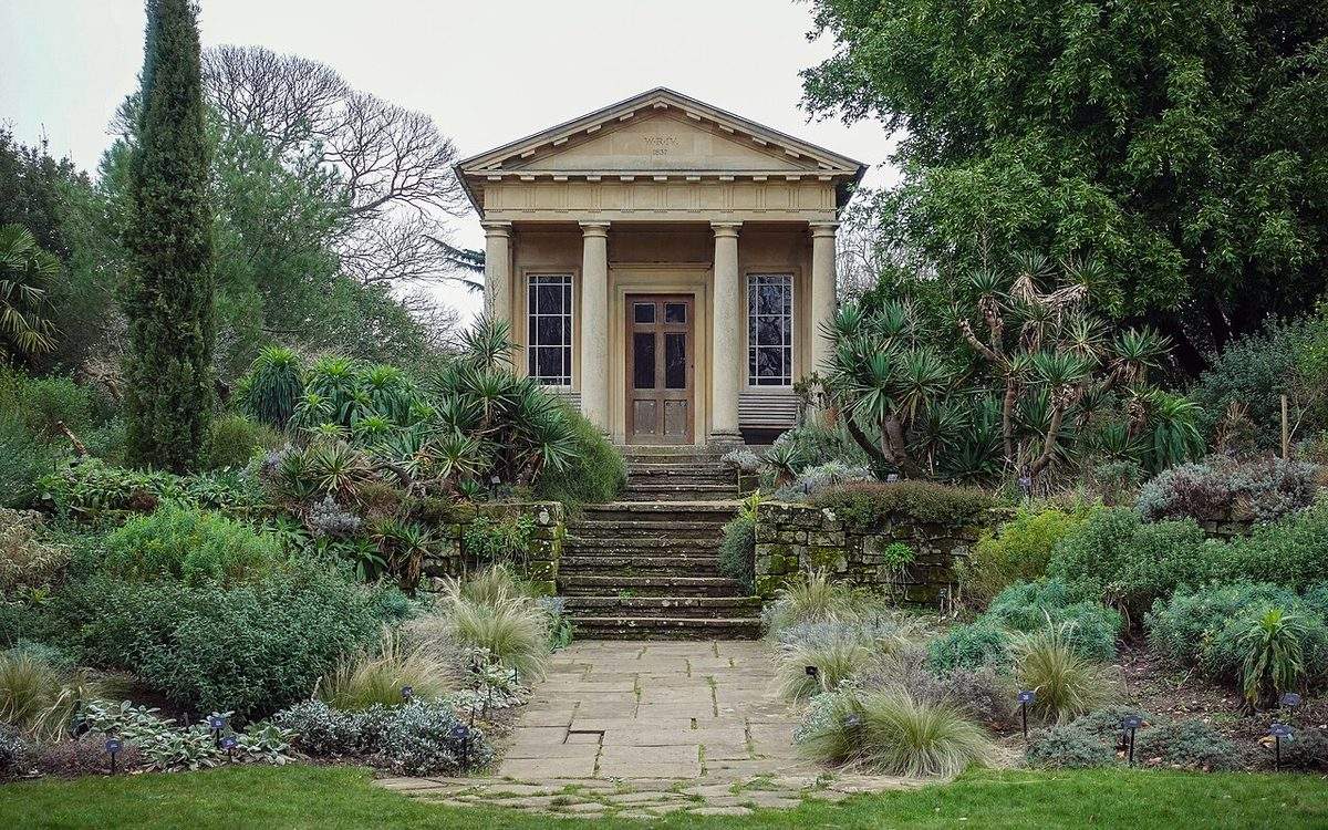 Jardin méditerranéen avec cyprès, yuccas, arbustes au feuillage gris et graminées le long d'une allée dallée