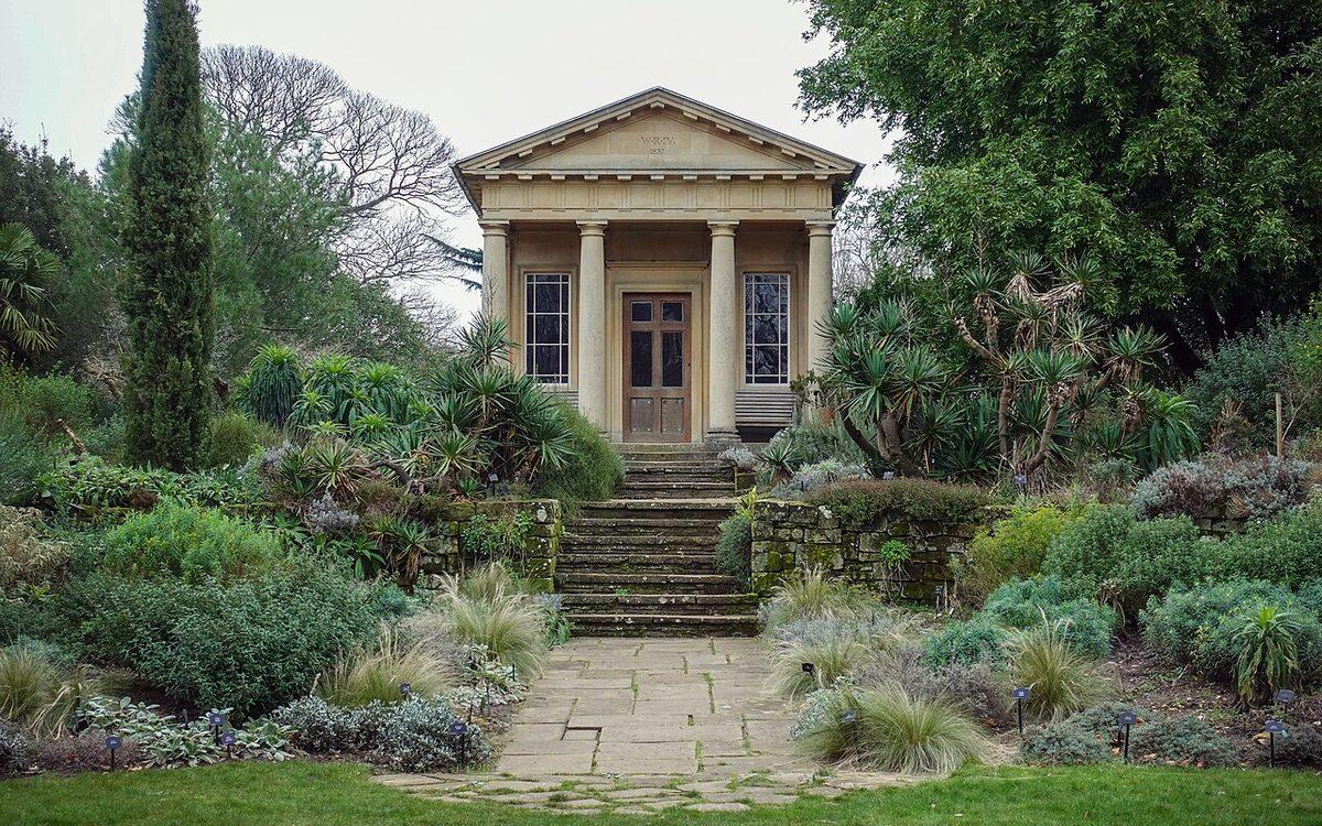 Jardin méditerranéen avec cyprès, yuccas, arbustes au feuillage gris et graminées le long d'une allée dallée